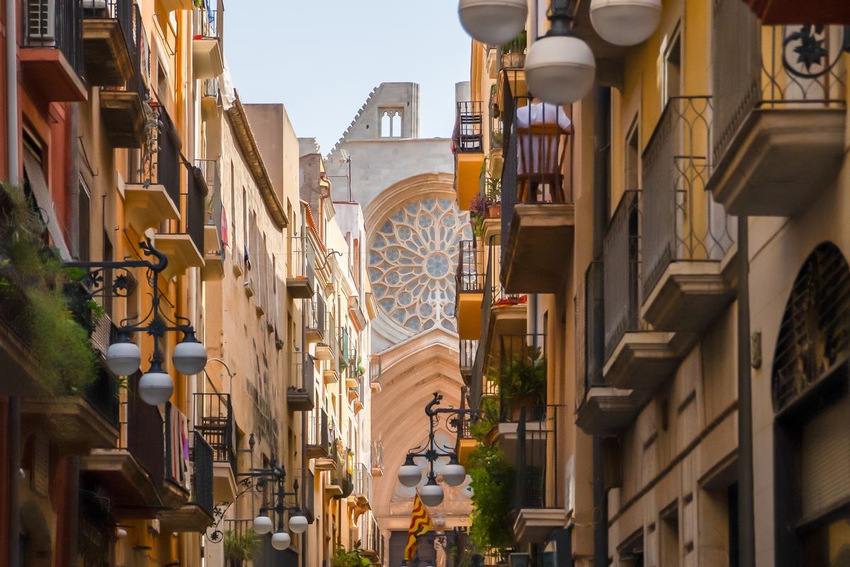 Carrer Major avec balcons, lanternes et la rosace de la cathédrale au fond.