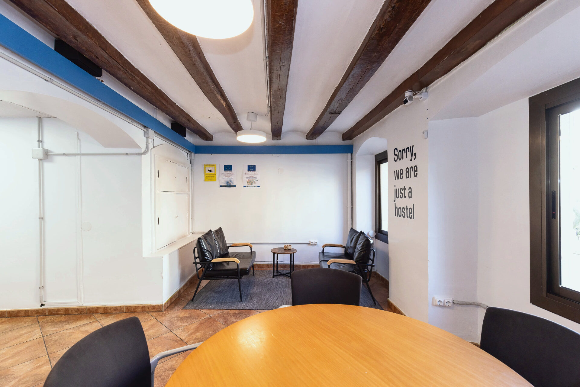 Sala comuna de l'hostal amb bigues de fusta originals, butaques de pell i taula rodona.