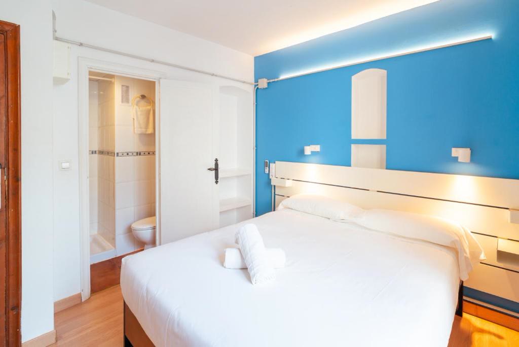 Habitació doble interior amb llit de matrimoni, paret blava i bany privat.