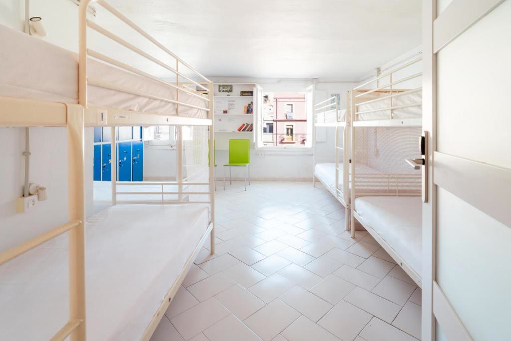 Dormitori compartit lluminós de 8 llits amb lliteres blanques i taquilles blaves.